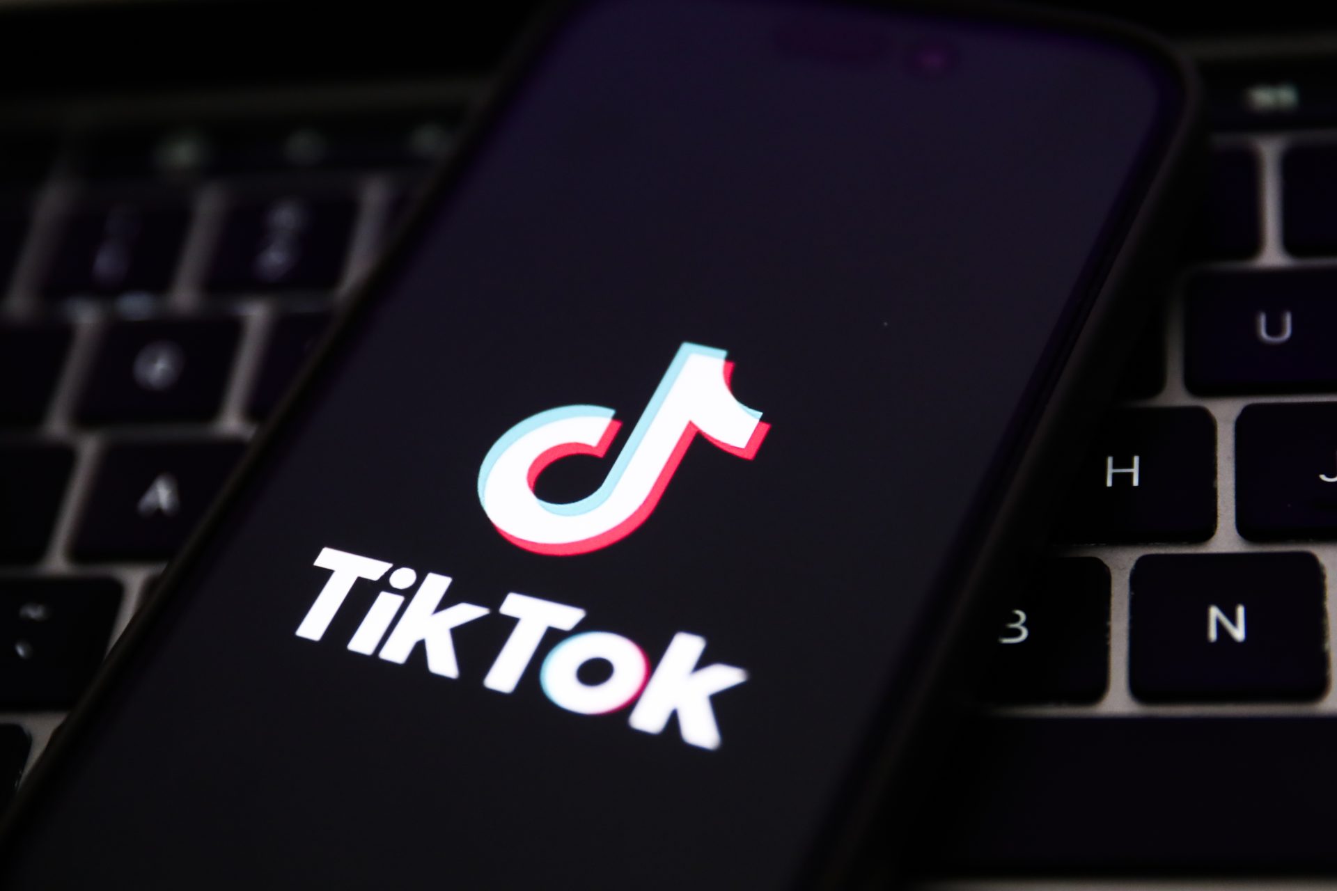 A laptop keyboard and TikTok logo displayed on a phone screen are seen in this illustration photo taken in Krakow, Poland on February 7, 2024.